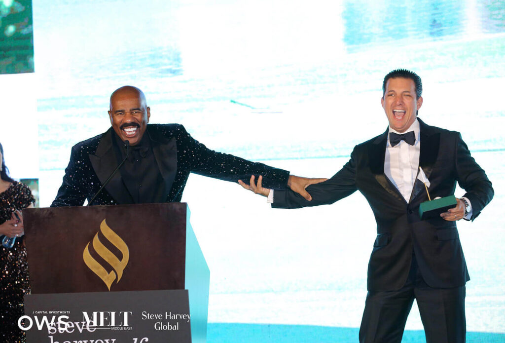 Steve Harvey at podium presenting award to guest