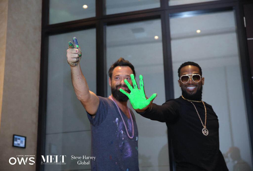Artist with guest showing painted hand
